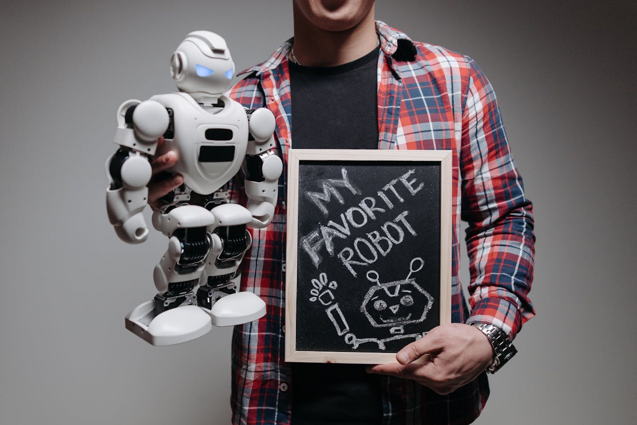 gallery-1 A person holding a white robot and a chalkboard with 'My Favorite Robot' written on it in a studio setting.