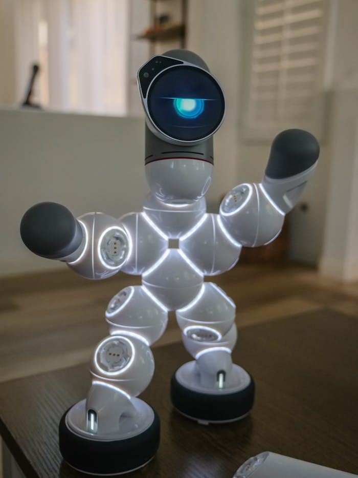 why-choose-us Modern walking robot with LED lights standing on a wooden surface indoors. Shallow focus emphasizes its futuristic design.